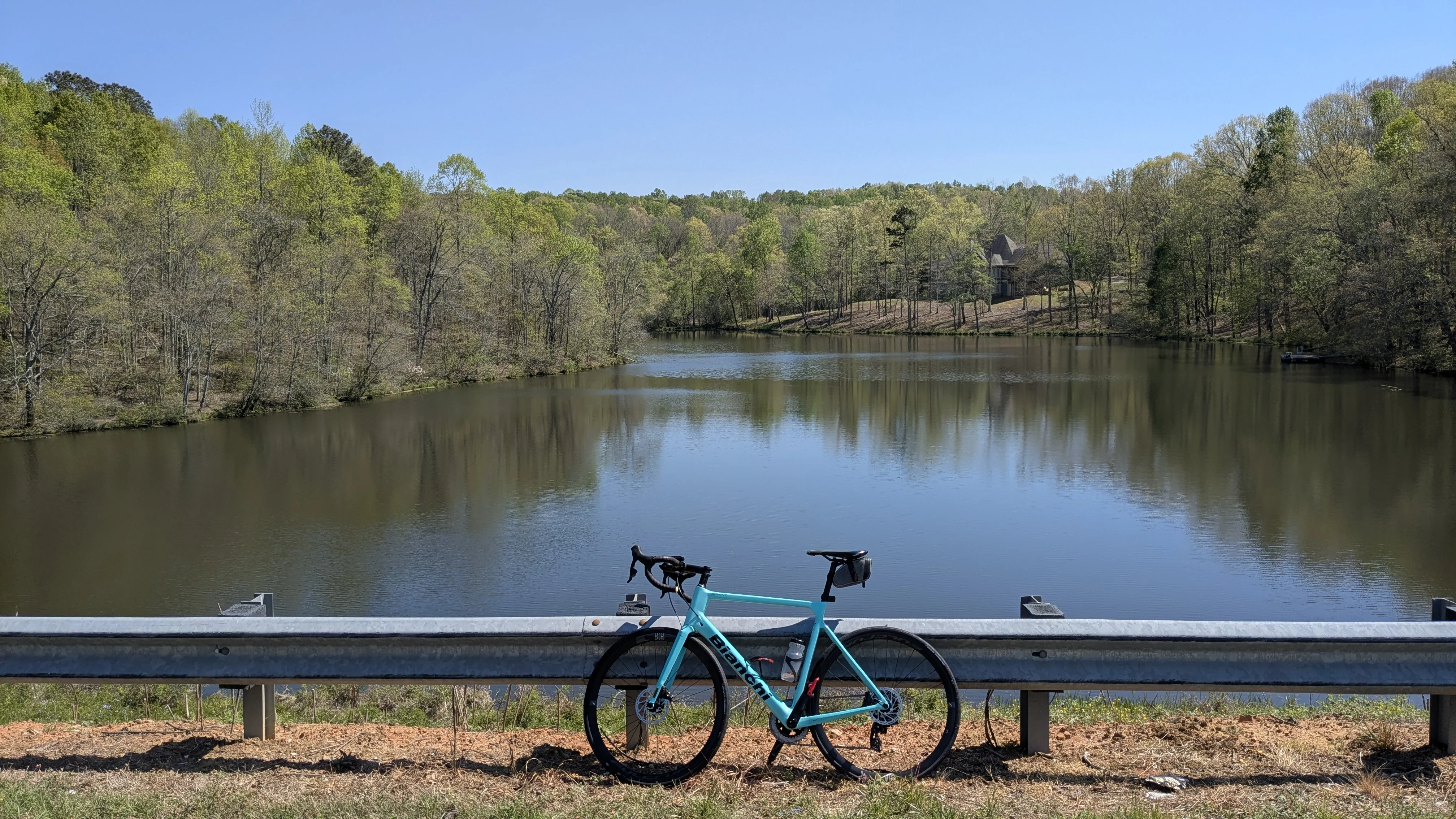 My bike next to a reservoir surrounded by trees 